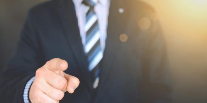 Confident businessman in a suit pointing forward, signifying leadership and focus.