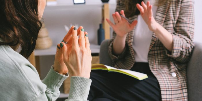 Two women engaged in a therapy session, communication and support in an office setting.